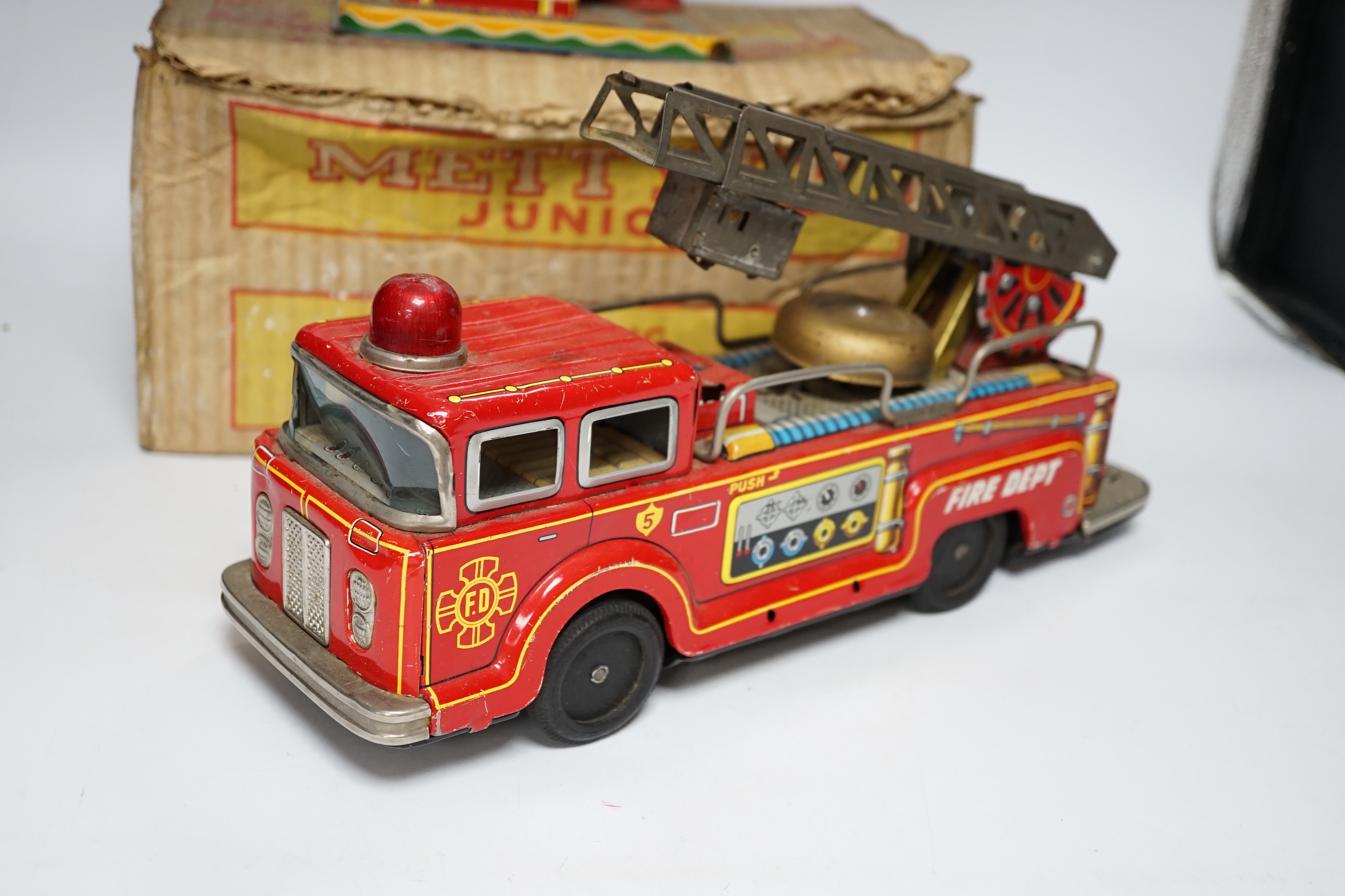 Four tinplate toys; a model of a 1920s taxi, a 1960s German made fire engine, an automaton clown, and a boxed Mettype Junior children’s typewriter